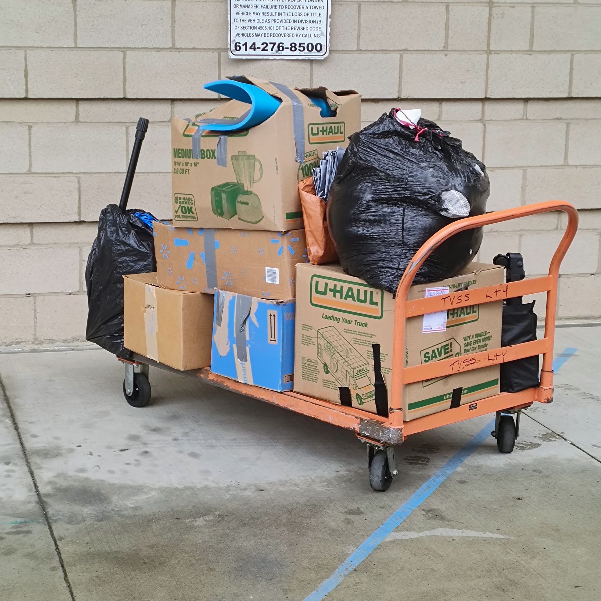 Fully loaded dolly cart with boxes and bags outside 