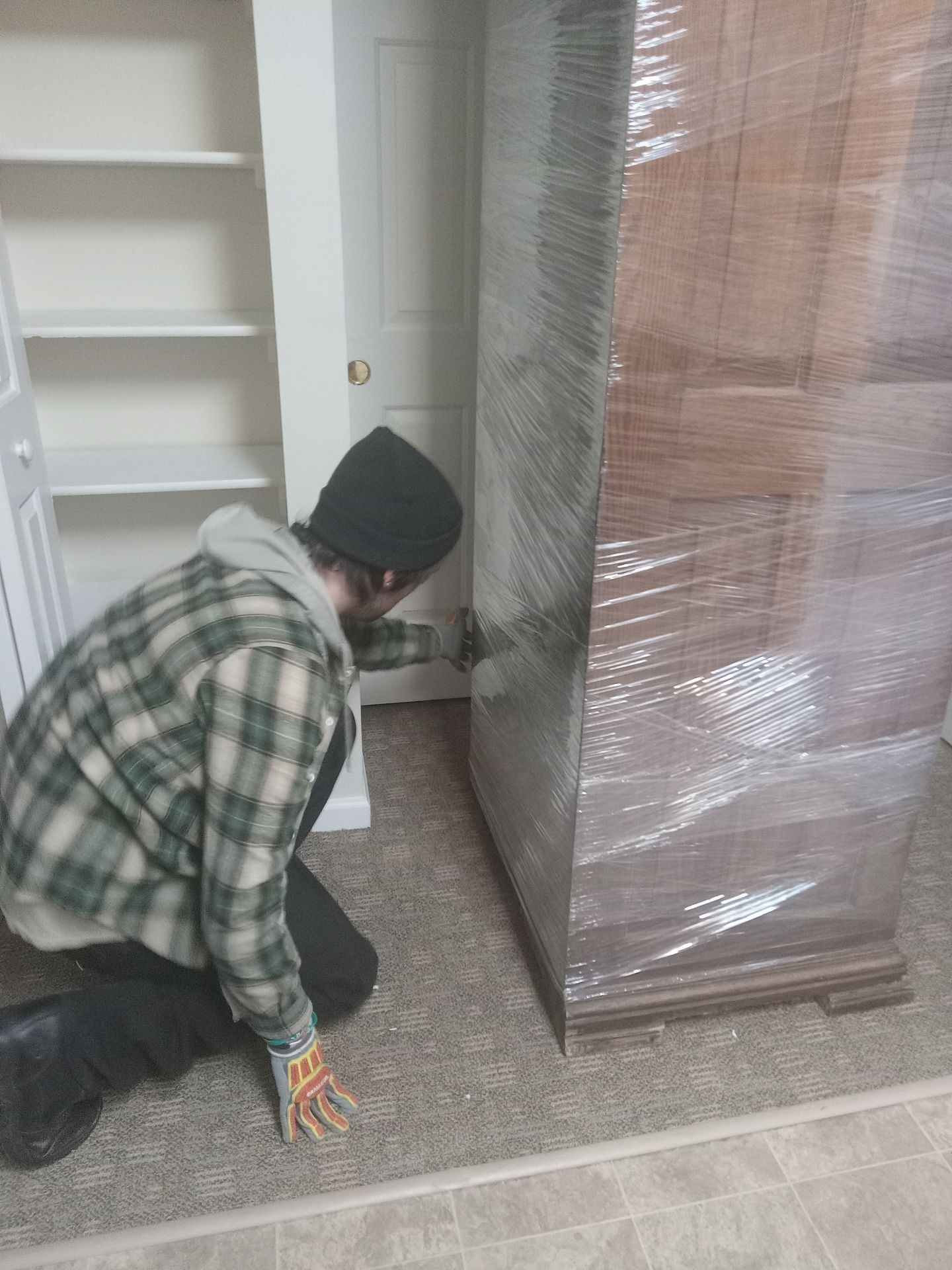 One of are guys shrink wrapping a big piece  of furniture 